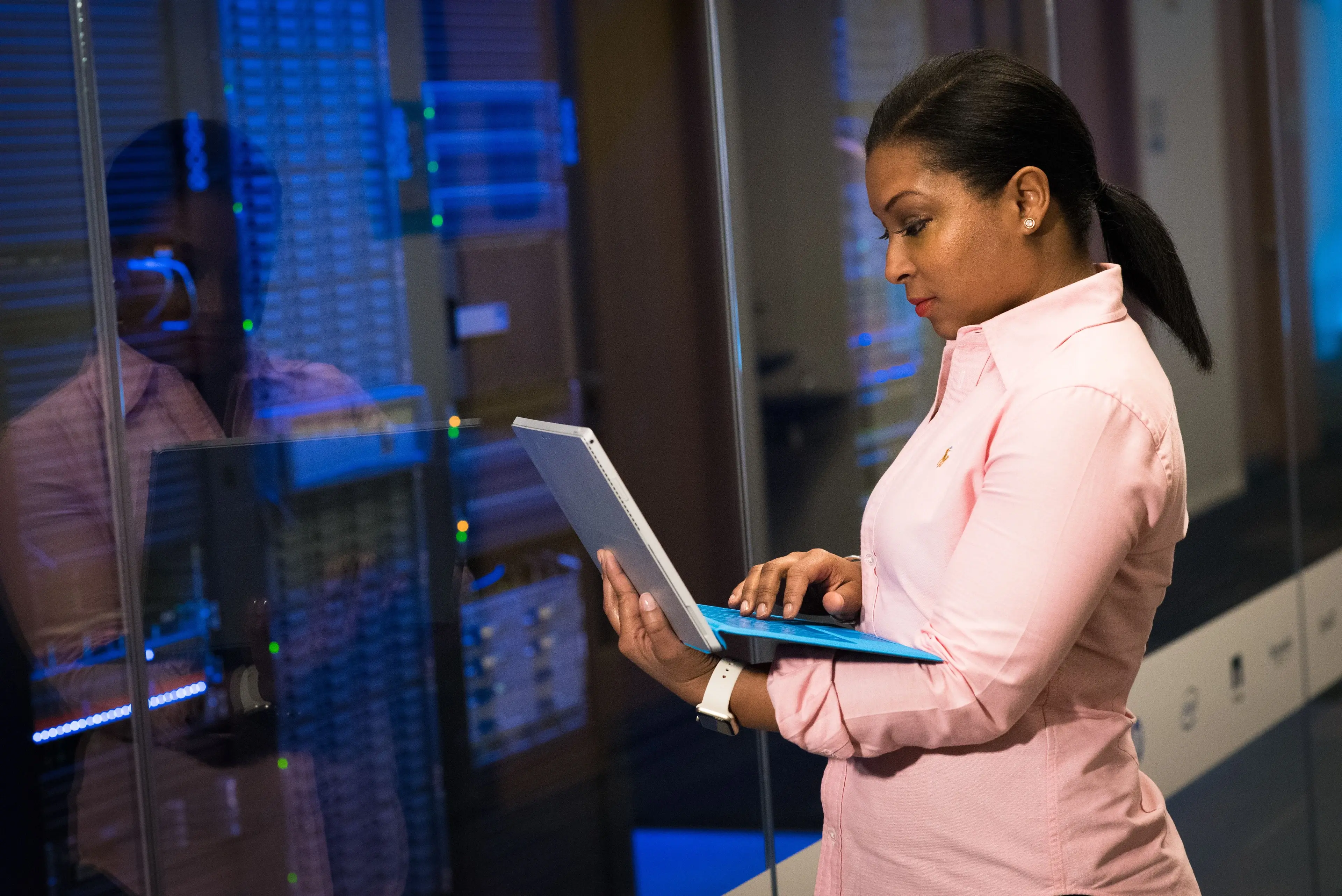 An engineer using a laptop beside server racks