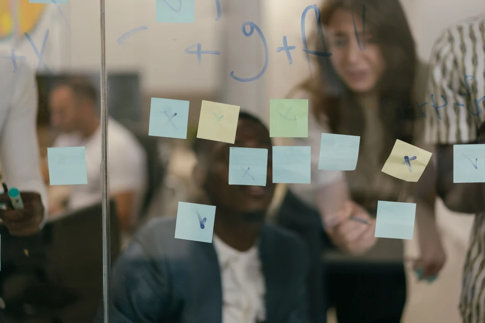 A team discussing priorities on a glass board covered in sticky notes